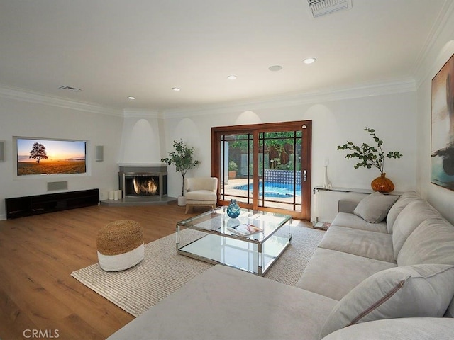 living room with a fireplace, ornamental molding, and light hardwood / wood-style flooring