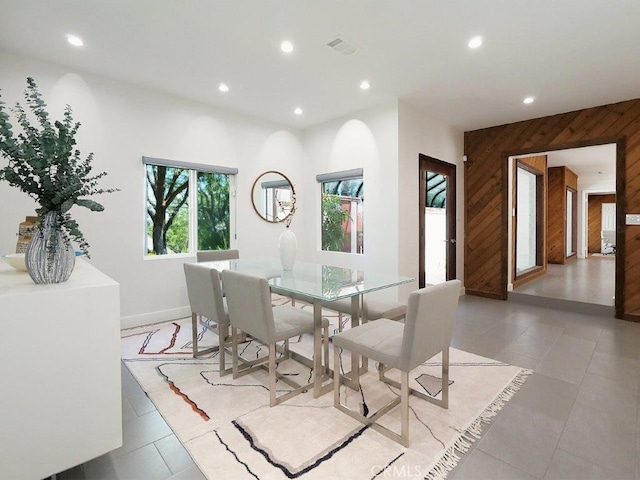 dining space featuring wood walls and light tile patterned flooring