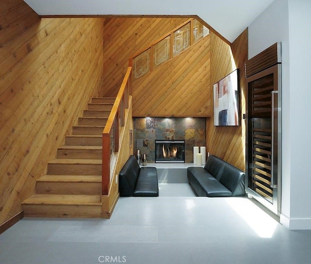 unfurnished living room featuring a towering ceiling, beverage cooler, and wooden walls