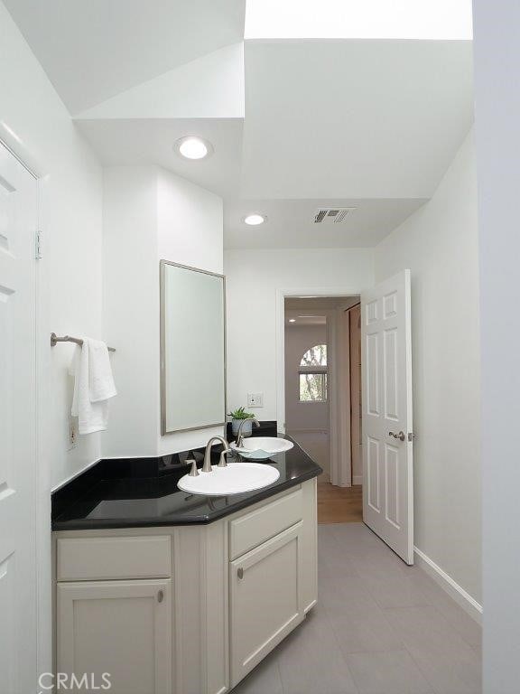 bathroom featuring tile patterned flooring, lofted ceiling, and vanity