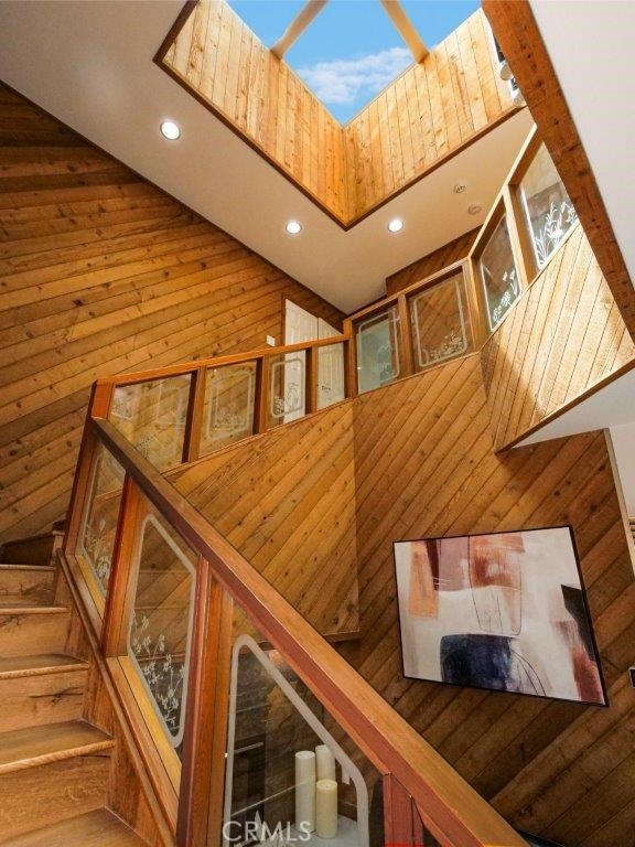 staircase with a towering ceiling and wood walls