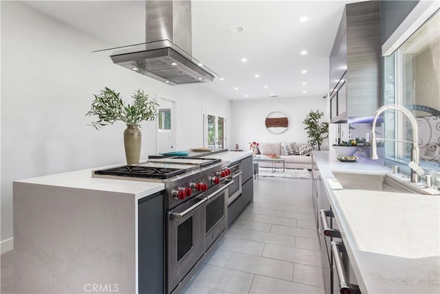 kitchen featuring sink, island range hood, range with two ovens, and a center island