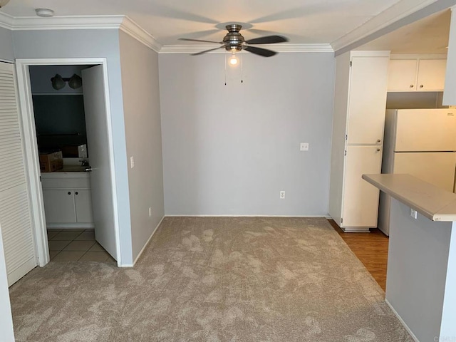 unfurnished dining area featuring light carpet, ceiling fan, and ornamental molding