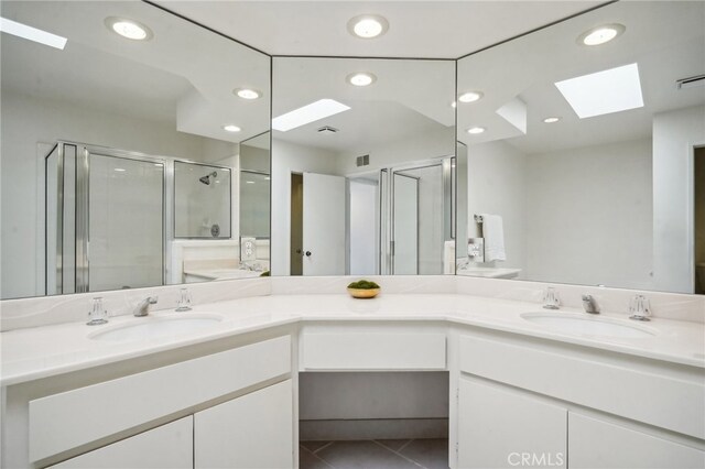 bathroom featuring vanity, walk in shower, a skylight, and tile patterned flooring