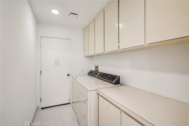 clothes washing area with cabinets and separate washer and dryer