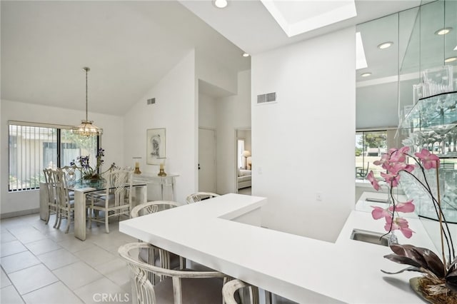 dining area featuring light tile patterned flooring, a healthy amount of sunlight, high vaulted ceiling, and a skylight