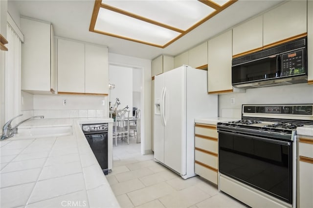 kitchen featuring tile countertops, white cabinetry, black appliances, and sink