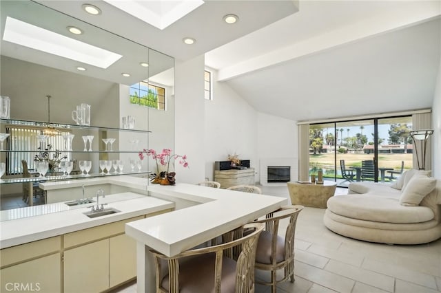 kitchen with vaulted ceiling with beams, cream cabinets, sink, pendant lighting, and light tile patterned floors