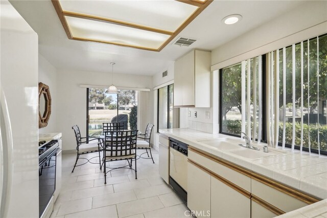 kitchen featuring tile countertops, sink, light tile patterned flooring, decorative light fixtures, and appliances with stainless steel finishes