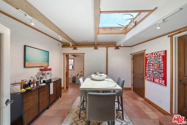 dining space with tile patterned flooring, a skylight, and track lighting