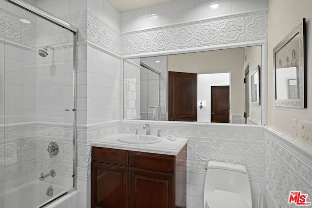 full bathroom featuring vanity, toilet, enclosed tub / shower combo, and tile walls