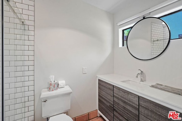 bathroom with vanity, toilet, and a tile shower