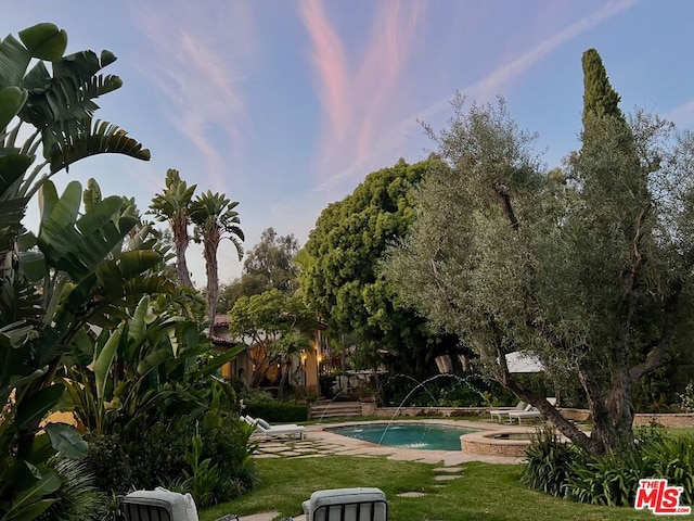 view of pool with a yard and pool water feature