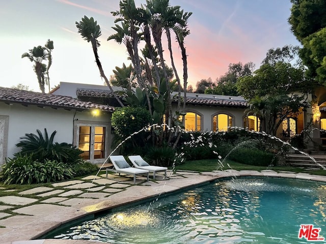 pool at dusk with a patio area