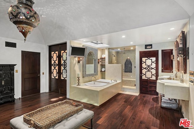 bathroom featuring wood-type flooring, a tub to relax in, lofted ceiling, and sink