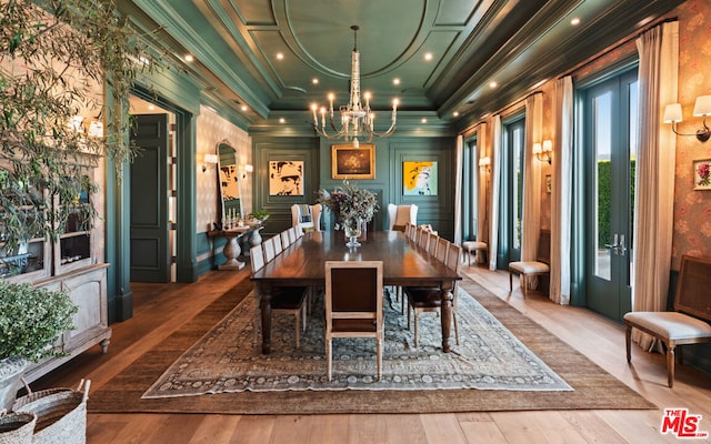 dining room with crown molding, wood-type flooring, a chandelier, and a raised ceiling