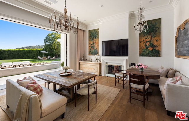 dining area with ornamental molding, an inviting chandelier, and hardwood / wood-style floors