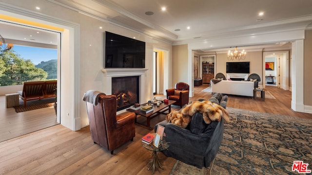 living room with ornamental molding, a chandelier, and light wood-type flooring