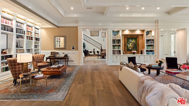 living room with built in features, wood-type flooring, ornamental molding, and beamed ceiling