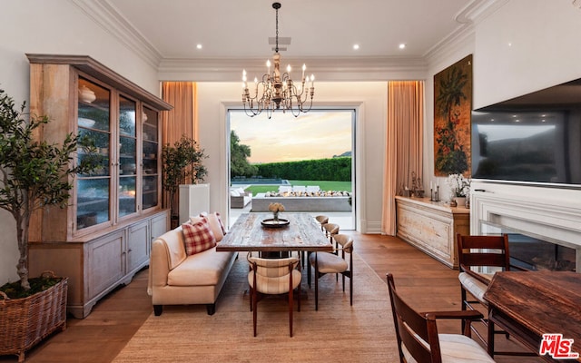 dining area with an inviting chandelier, crown molding, and light hardwood / wood-style floors