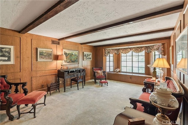 living area featuring light carpet, beam ceiling, a textured ceiling, and wooden walls