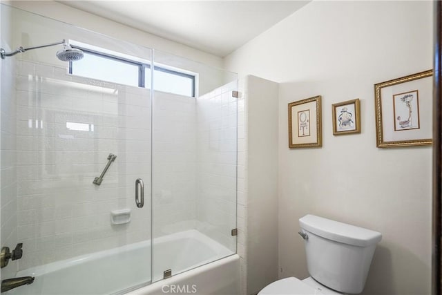 bathroom with combined bath / shower with glass door and toilet