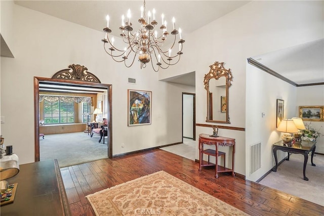 interior space featuring ornamental molding, wood-type flooring, lofted ceiling, and an inviting chandelier