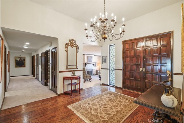 carpeted foyer entrance featuring an inviting chandelier