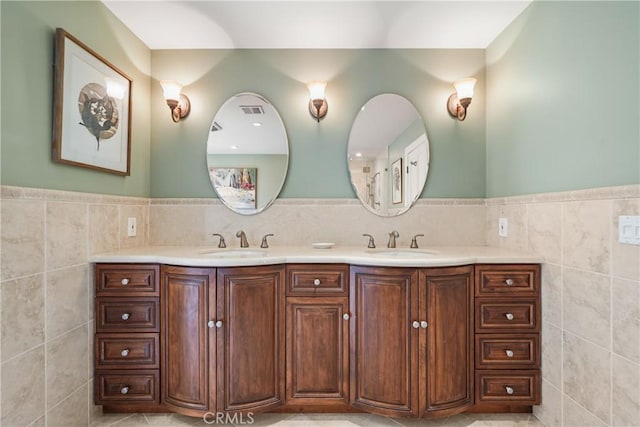 full bathroom with a sink, tile walls, and double vanity