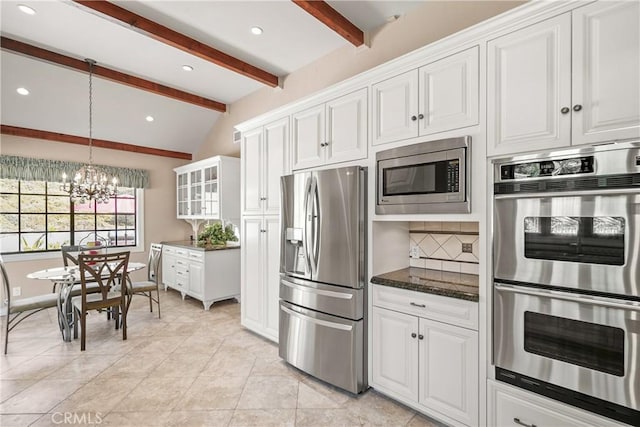 kitchen featuring white cabinetry, an inviting chandelier, lofted ceiling with beams, backsplash, and appliances with stainless steel finishes