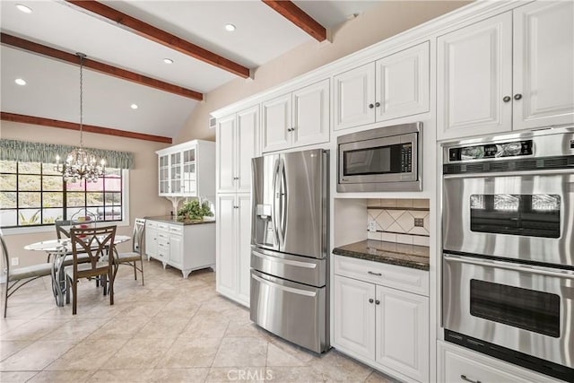 kitchen featuring decorative backsplash, dark stone counters, lofted ceiling with beams, appliances with stainless steel finishes, and white cabinetry