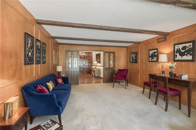 living area featuring carpet floors, beamed ceiling, visible vents, and a decorative wall