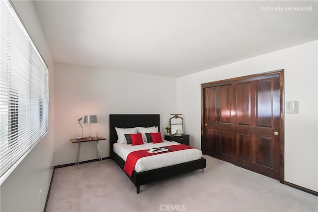 bedroom with baseboards, a closet, and light colored carpet