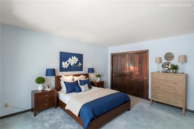 bedroom with a closet, light carpet, and baseboards