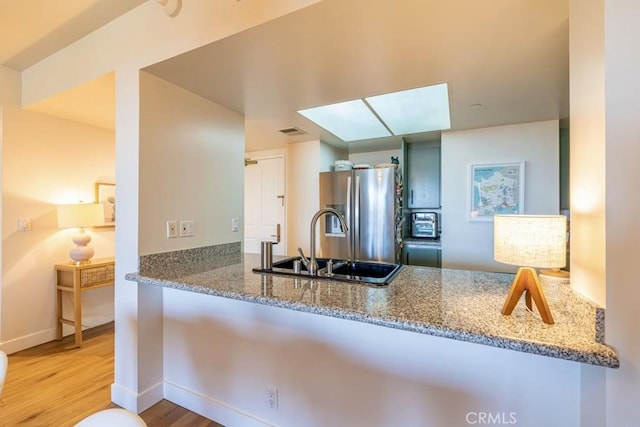 850 E Ocean Blvd Unit 613, Long Beach, CA 90802 - kitchen featuring freestanding refrigerator, a sink, wood finished floors, and stone counters