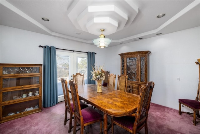 carpeted dining area featuring a tray ceiling and french doors