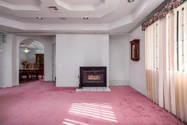 unfurnished living room with light colored carpet and a raised ceiling