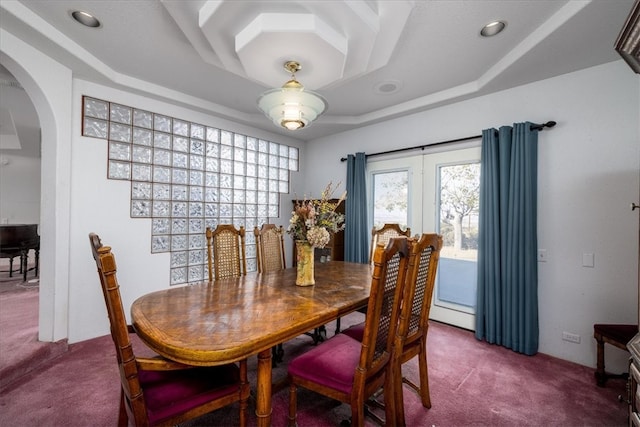 carpeted dining area with a raised ceiling