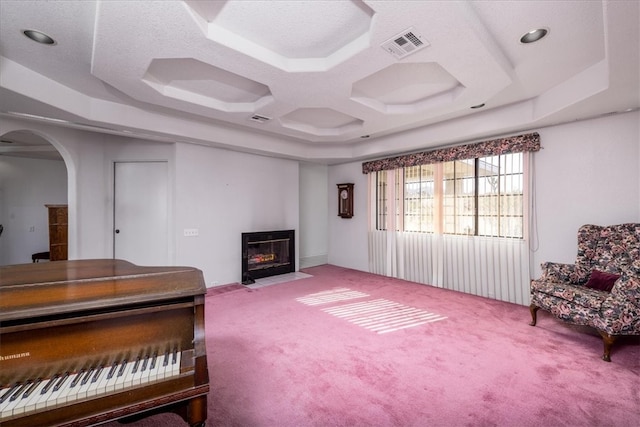 sitting room with carpet, a textured ceiling, and a tray ceiling