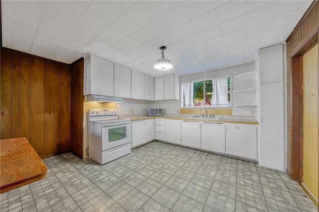 kitchen featuring electric stove, wooden walls, white cabinets, and pendant lighting