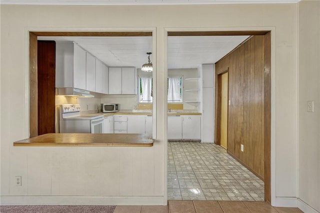 kitchen with wood walls, white cabinets, stainless steel appliances, and decorative light fixtures