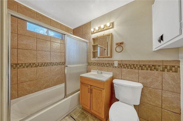 full bathroom with tile patterned floors, vanity, shower / bath combination with glass door, tile walls, and toilet