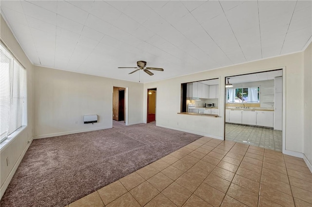 tiled spare room featuring ceiling fan, sink, and heating unit