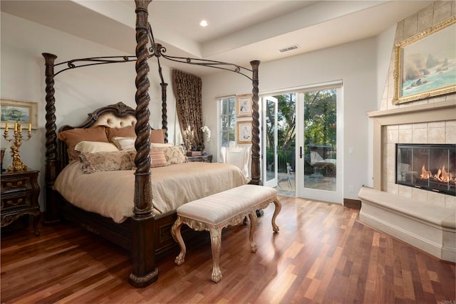 bedroom with wood-type flooring, access to exterior, and a tile fireplace