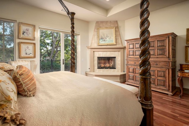 bedroom with dark wood-type flooring, access to outside, and a fireplace