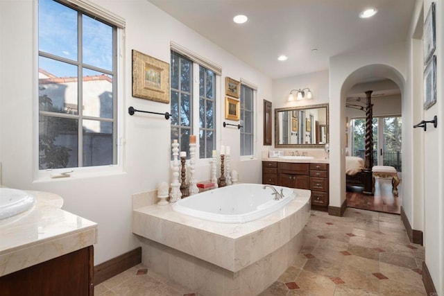 bathroom featuring a relaxing tiled tub, vanity, and ceiling fan