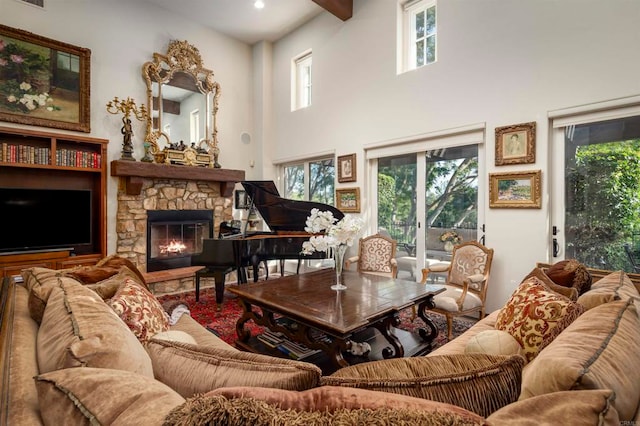 living room featuring a towering ceiling, a healthy amount of sunlight, and a stone fireplace