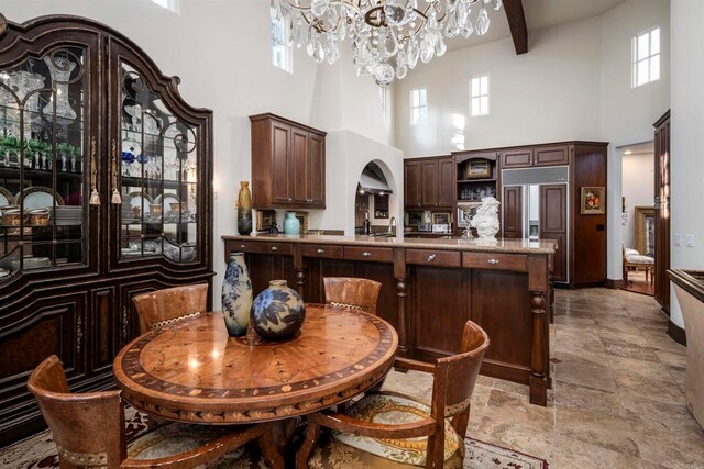 kitchen with a high ceiling, dark brown cabinets, and beamed ceiling