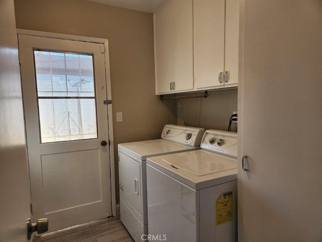 clothes washing area with washing machine and clothes dryer and cabinets