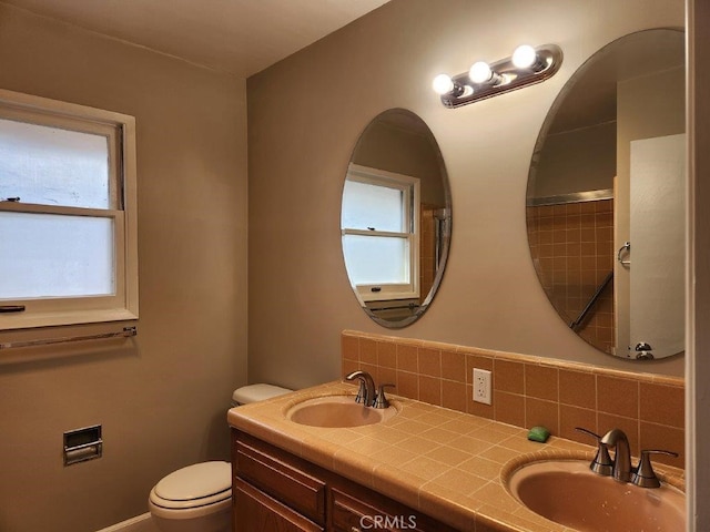 bathroom with decorative backsplash, vanity, toilet, and a healthy amount of sunlight